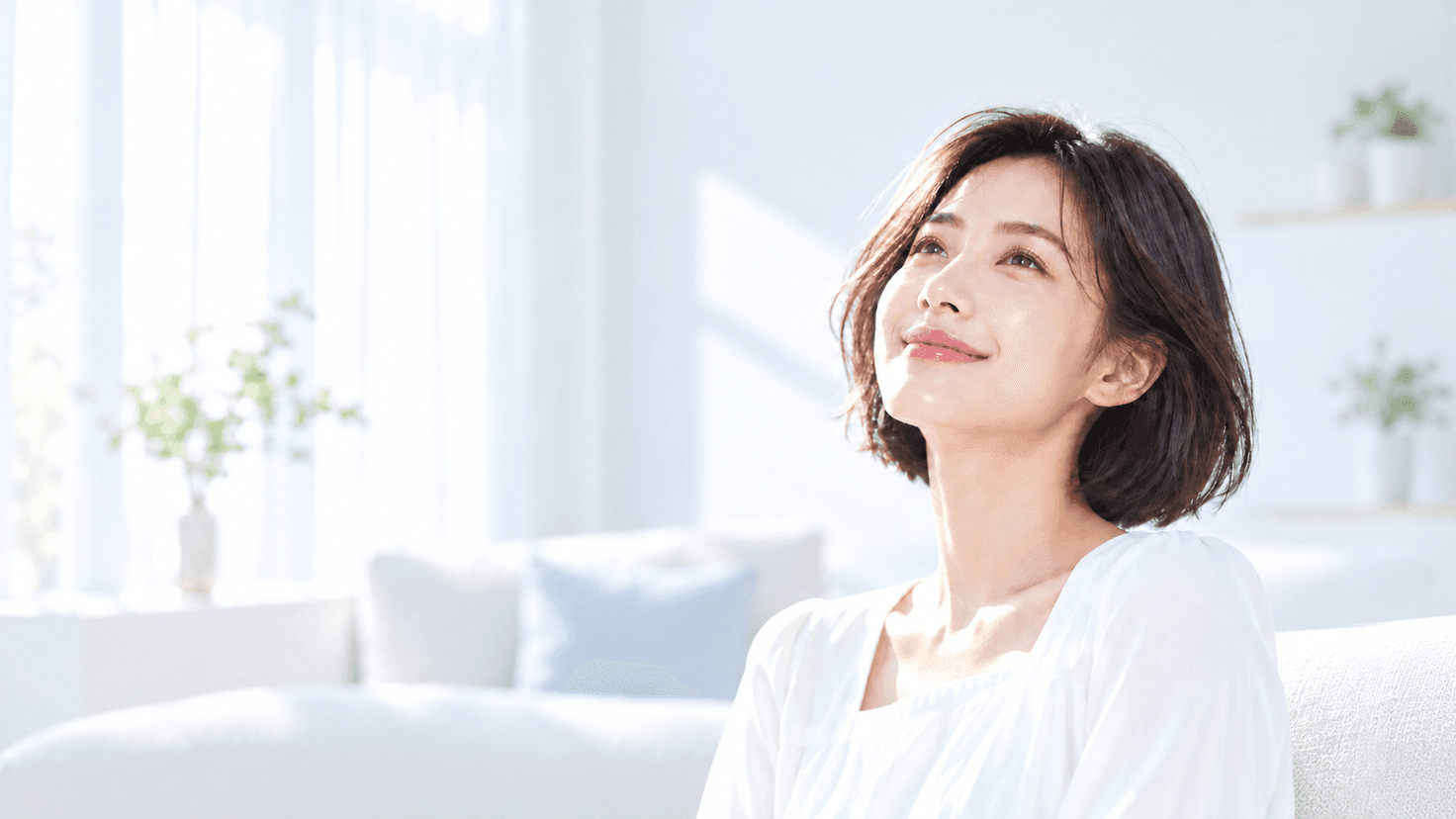 밝은 실내에서 창가 빛을 받으며 미소 짓는 단발머리 여성